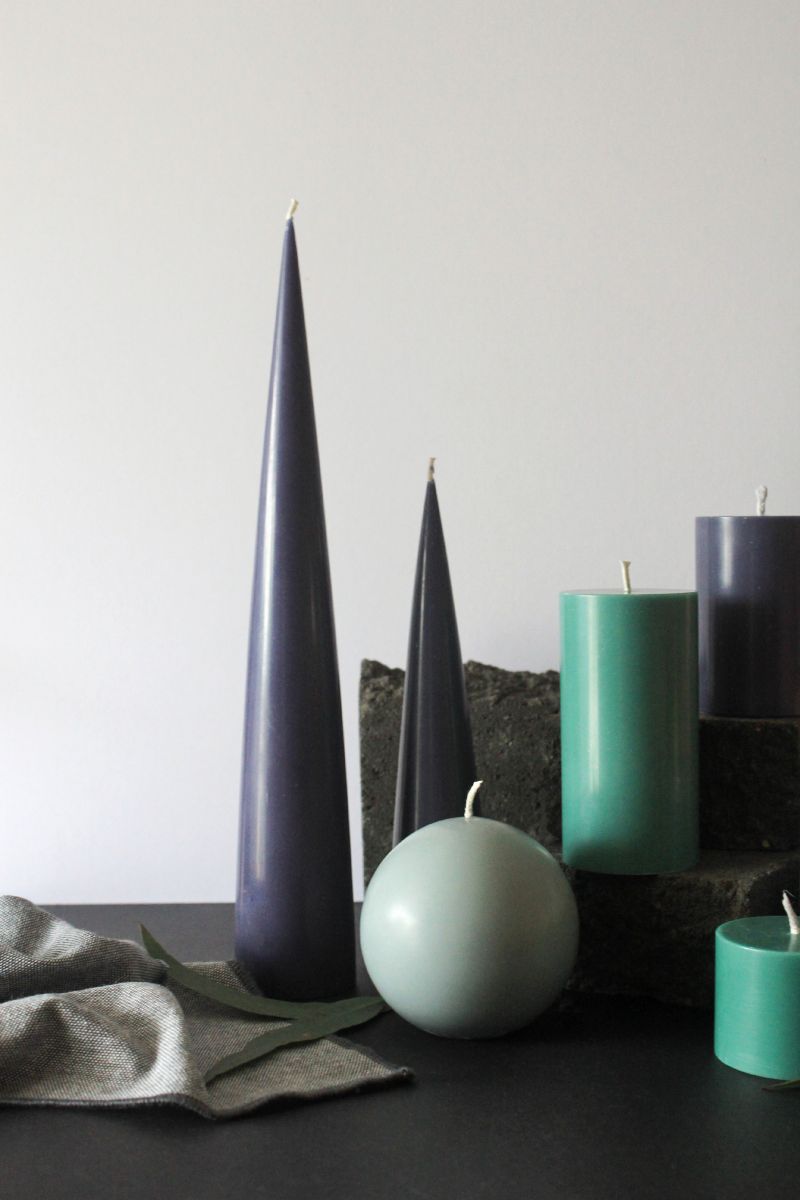 image of green and navy candles in cone ball and pillar shaped on mantelpiece